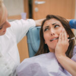 kobieta z bolącym zębem na fotelu dentysty