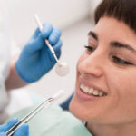 Dentysta trzyma implant zębowy przed twarzą pacjenta