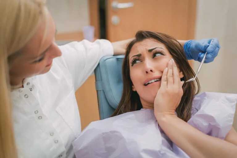 kobieta z bolącym zębem na fotelu dentysty